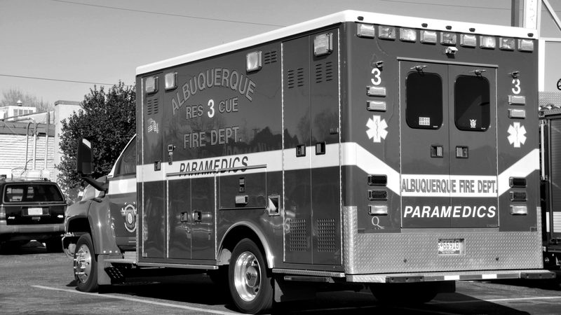 A fire department ambulance parked on a street, in black and white