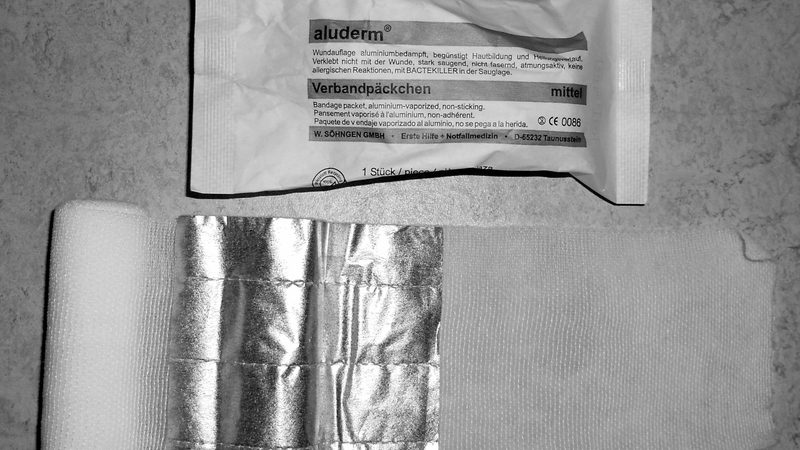 A closed individual first aid kit pouch or a packaged compression bandage laid on a flat surface, with no people visible.